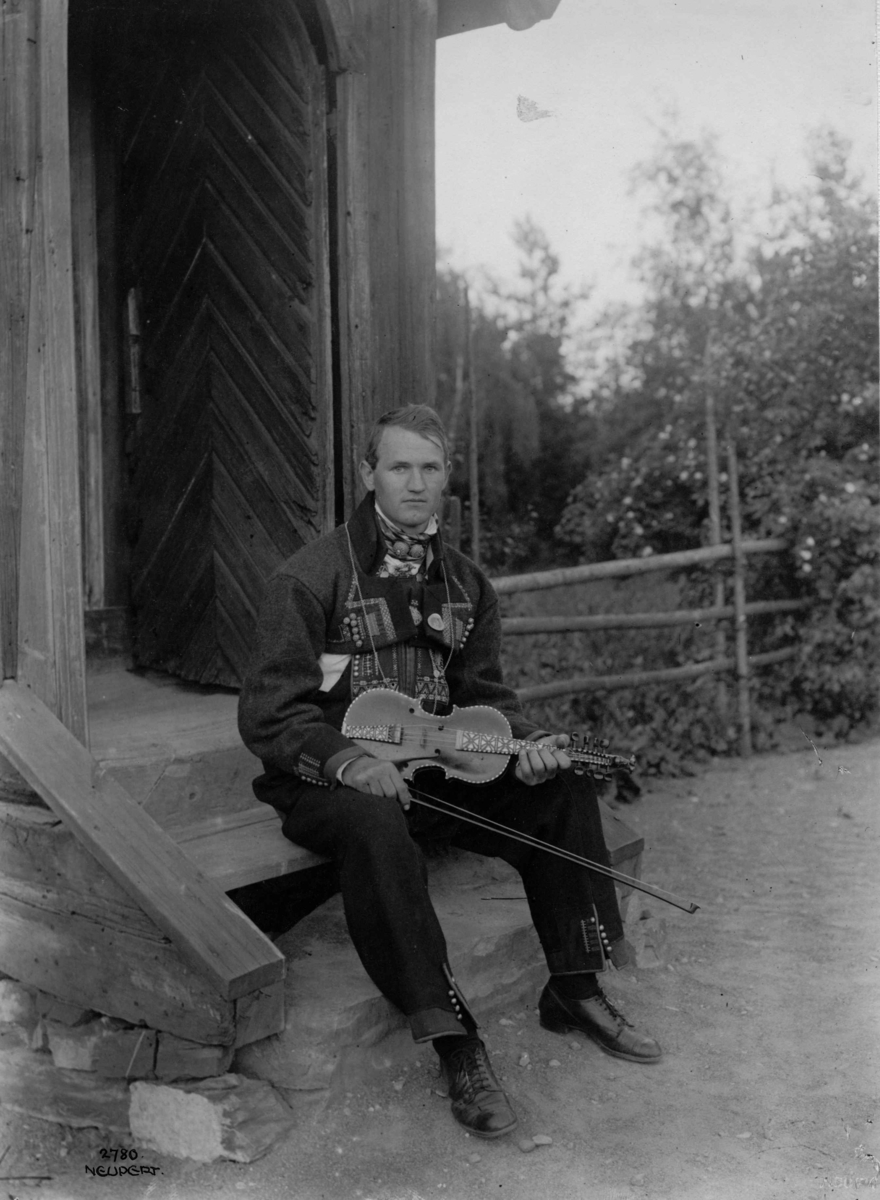 Hermann Christian Neupert, Felespiller med hardingfele 1925. Bunadkledd. Sittende på en trapp.