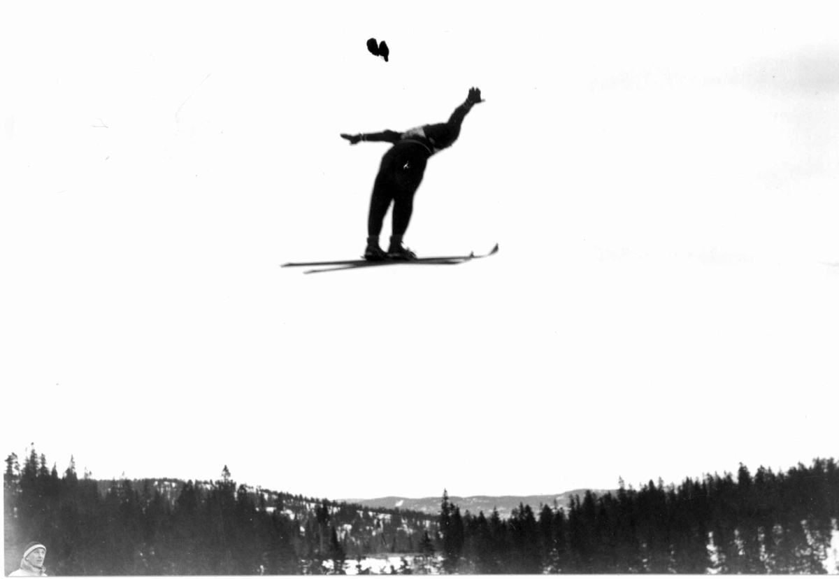 Hermann Christian Neupert, Ski. Hopprenn. Holmenkollen, Oslo 1934. Hopper i svevet. Nordmarka ses i bakgrunnen.