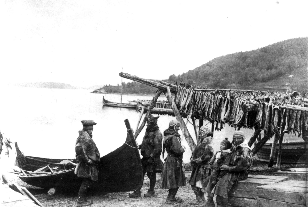 Axel Lindahl, Karesuando-samer ved robåt på sommeropphold i Lyngseidet ca. 1884-90. I bakrunnen henger tørrfisk på et stativ kalt for hjell.