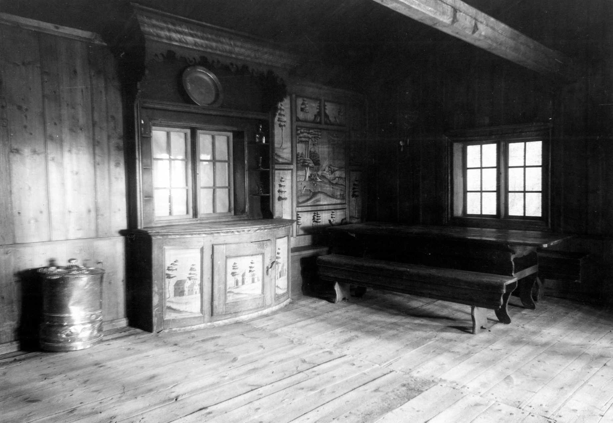 Gisle Midttun, Hofsløkka, Elverum, Sør-Østerdal, Hedmark. Interiør fra stua med skap, bord, benker og veggdekorasjoner. Nå på Glomdalsmuseet.