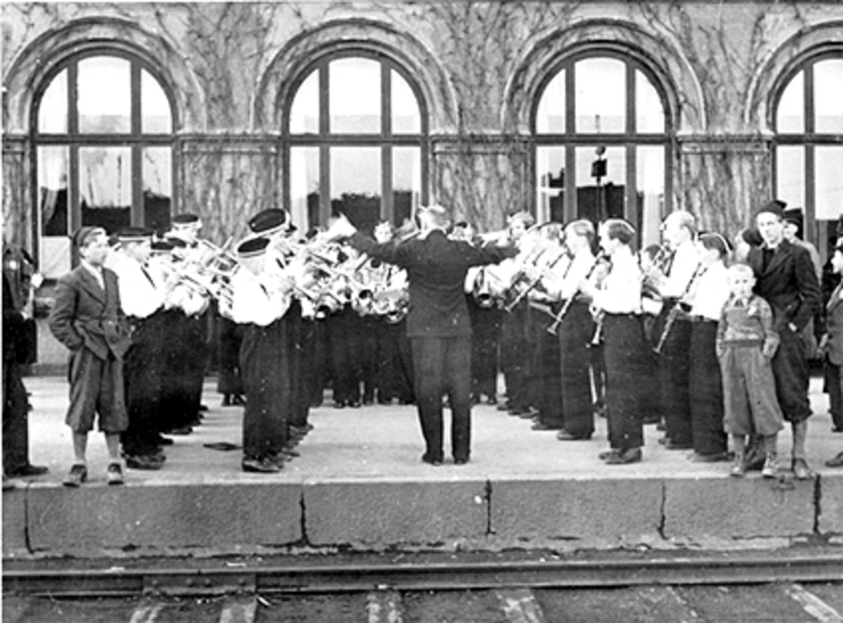 Anno Domkirkeodden, 17 MAI, HAMAR GUTTEMUSIKKORPS SPILLER PÅ HAMAR JERNBANESTASJON, PÅ PERRONGEN UTENFOR JERNBANERETAURANTENSE HHB 10049