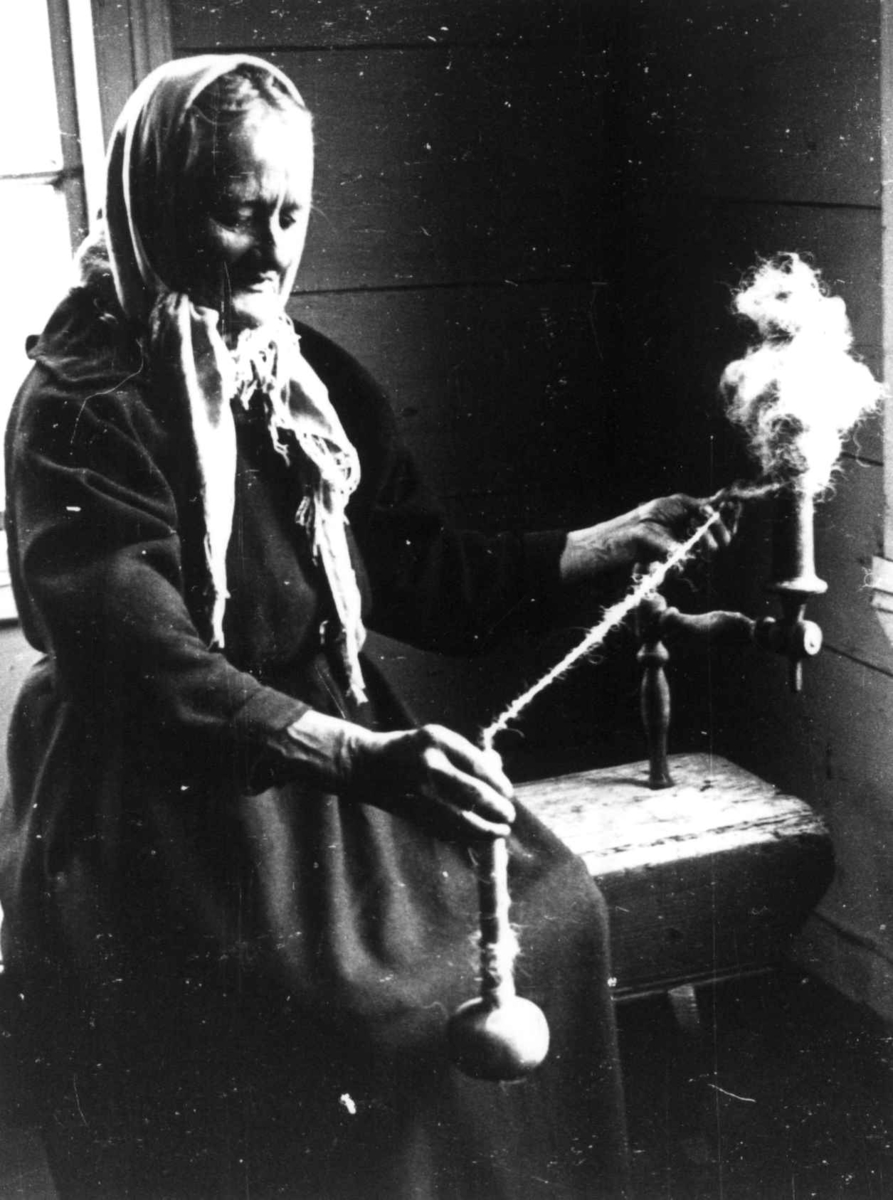 Anna Grostøl, Ragnhild Åvitsland spinner kutagl og grov ull på en liten hjemmelaget håndrokk i tre. Eiken, Hægebostad, Vest-Agder 1941.