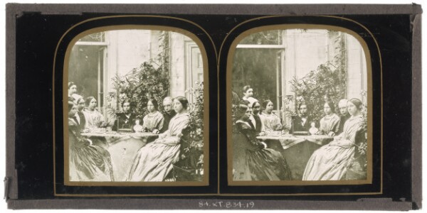 Unknown, [Group of unidentified British men and women seated around a table with a small bust of a man at center]
