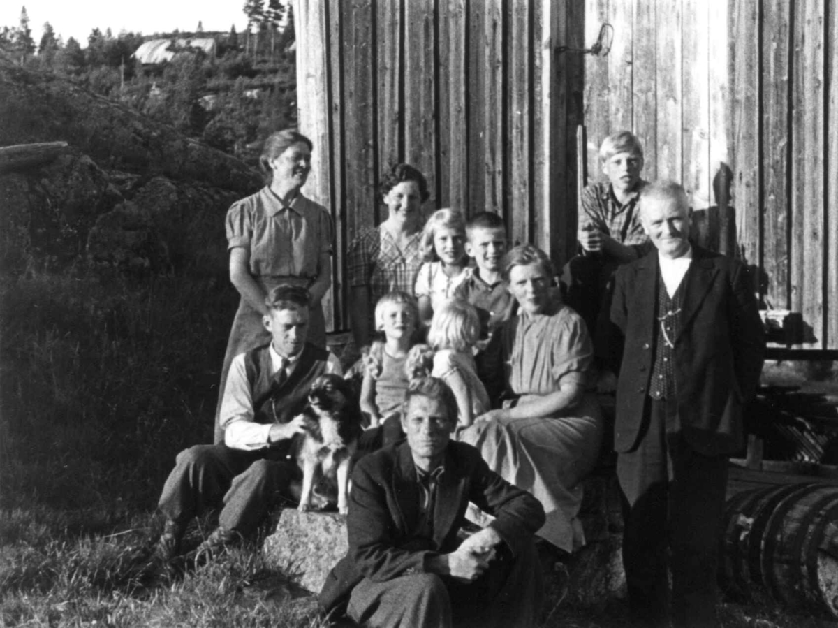 Anna Grostøl, Gruppefoto av voksne, barn og en hund utenfor en husvegg. Fjermedal 1941.