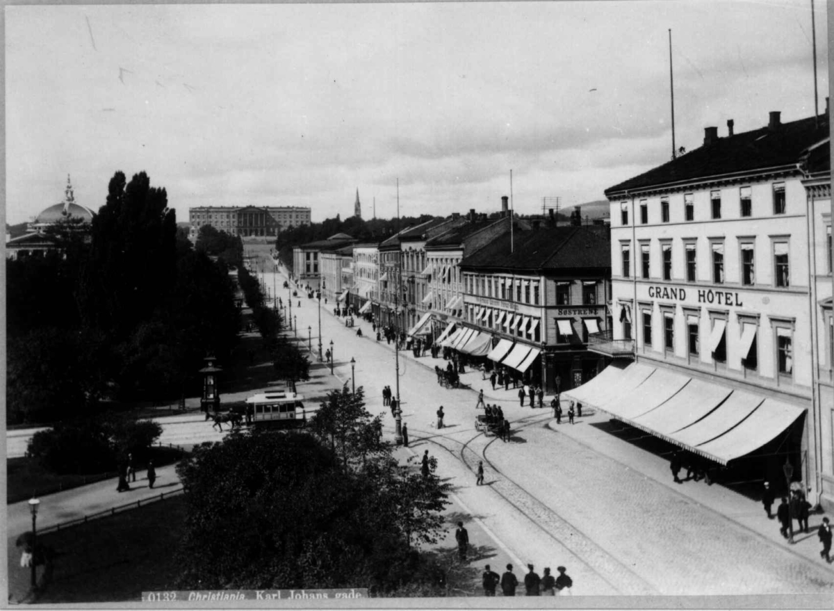 Axel Lindahl, Karl Johans gate, Oslo 1885-90. Gatebilde med Grand Hotel, Eidsvolls plass, mennesker og hestetrikk. Sett mot Slottet.
