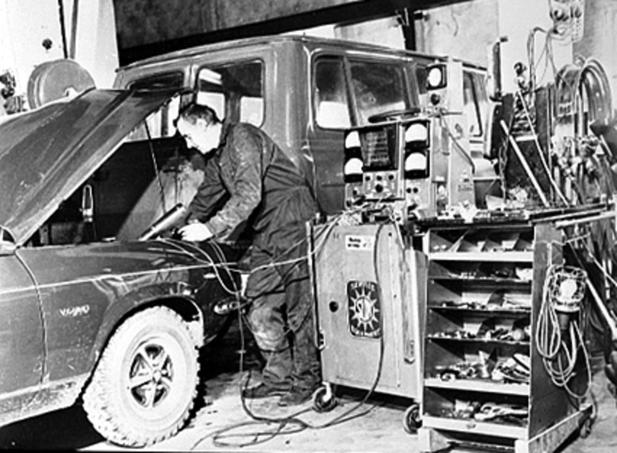 Anno Domkirkeodden, INTERIØR BILVERKSTED, OUSTAD MEK. VERKSTED, BILMEKANIKKER FORETAR KONTROLL AV BILMOTOR