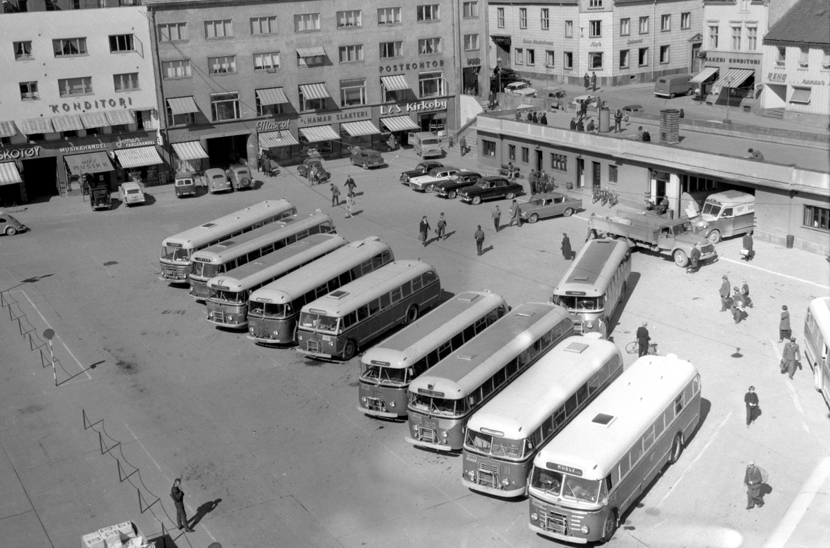 Anno Domkirkeodden, ØSTRE TORG MED MANGE BUSSER OG DROSJER, POSTHUSTRAPPA, HÅKONSGATE. RUTEBILSTASJONEN, M. STEEN BYGGET, MUSIKKHANDEL, JONERS FARGEHANDEL, MASCOT PARFYMERI, HAMAR SLAKTERI, L. & S. KIRKEBY, I 2 ETASJE POSTKONTORET. BUSSER FRA HAMAR OG OMLAND BILRUTER