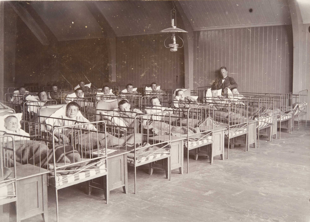 Berg & Høeg, Sovesalen på Bastøy skolehjem, interiør, senger, Bastøya, ca. 1903. Elever og en ansatt.