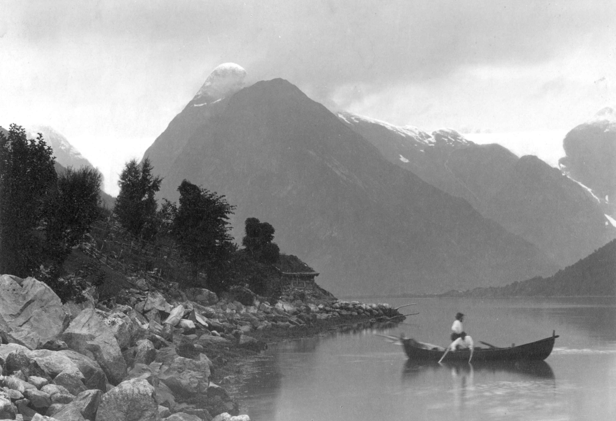 Axel Lindahl, Parti fra Fjærlandsfjorden, Balestrand, Sogn. To personer i robåt. Steinbu. Fjell i bakgrunnen.