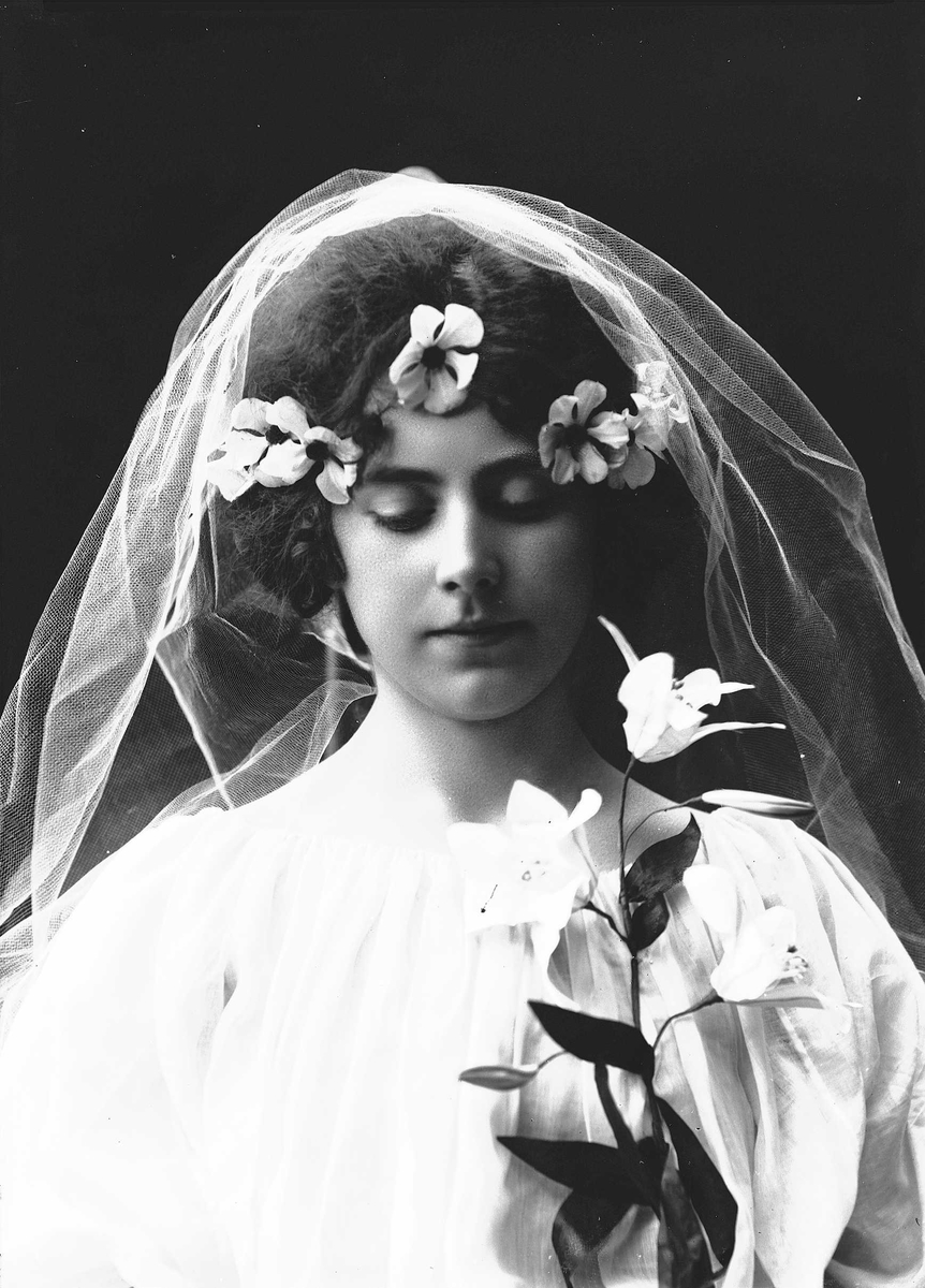 Solveig Lund, Studioportrett av kvinne i kostyme, oppsatt hår og slør - hvit overdel og blomster i håret.