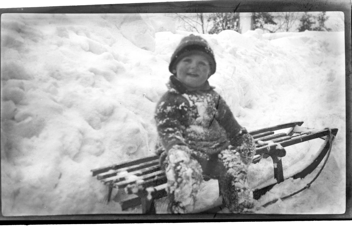 Rolf Sr. Sundt, Julius Sundt sitter på en kjelke med masse snø rundt seg, Ville Knyggen. Fotografert 1918-1919.