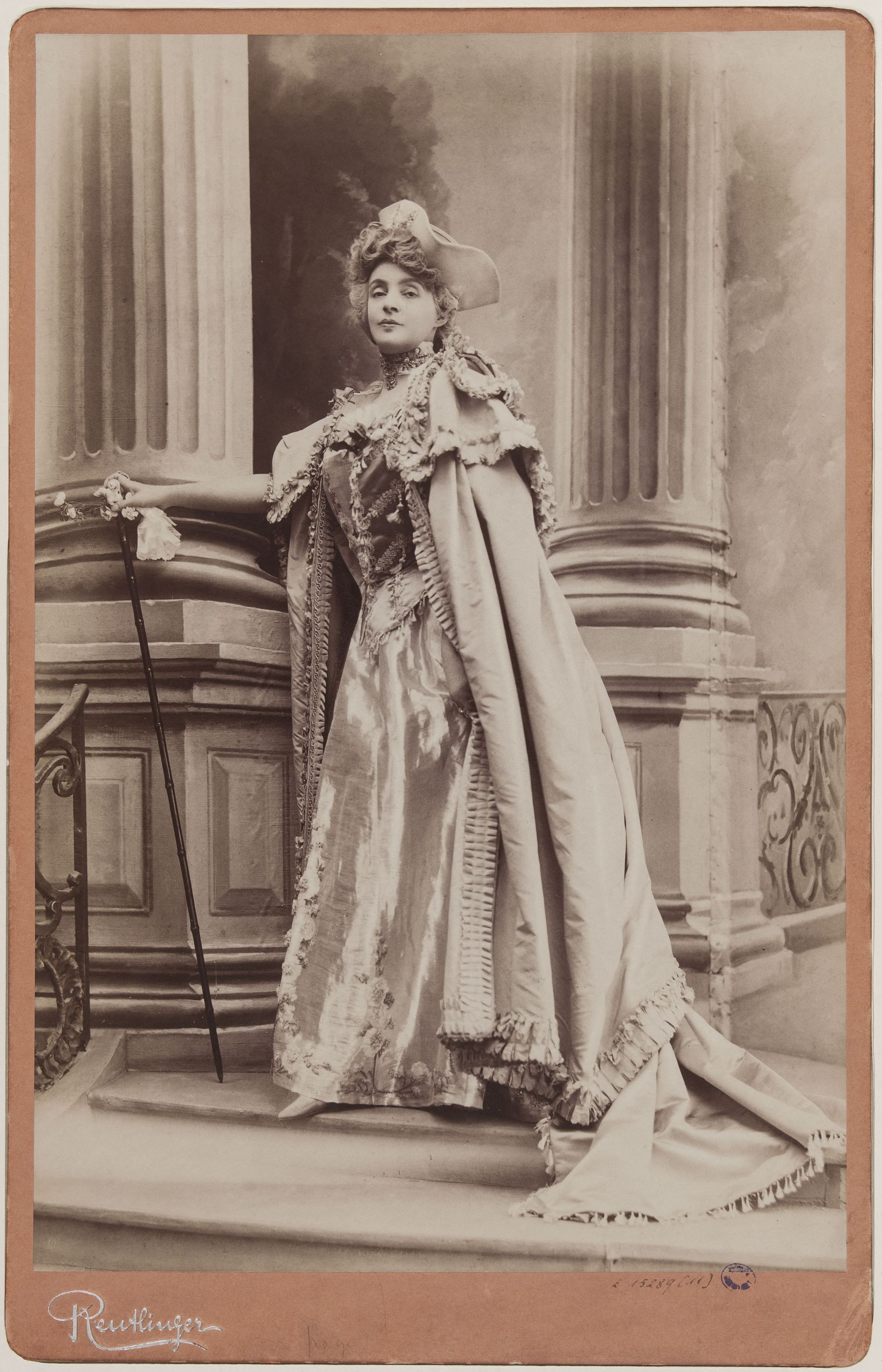 Charles Reutlinger, Portrait de Réjane (Gabrielle Réju, dite), (1856-1920) debout devant un escalier avec une canne
