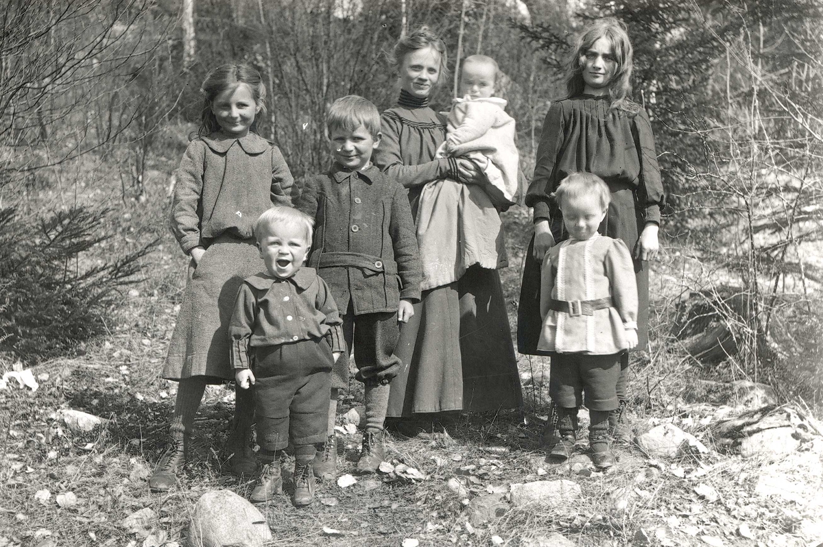 Axel Quinsgaard Wiborg, Familiegruppe, Margrethe Q. Wiborg, fotografens kone, med barn/stebarn utendørs, Digerud, Frogn 1906. Fra venstre: Gudrun (Dudo), Thor, Axel, Margrethe med minste sønn, Simon på armen, Karen Mathilde (Lillemor) og Halvor Nicolay. Fra serie tatt av iseksportør Axel Quinsgaard Wiborg (d. 1944).