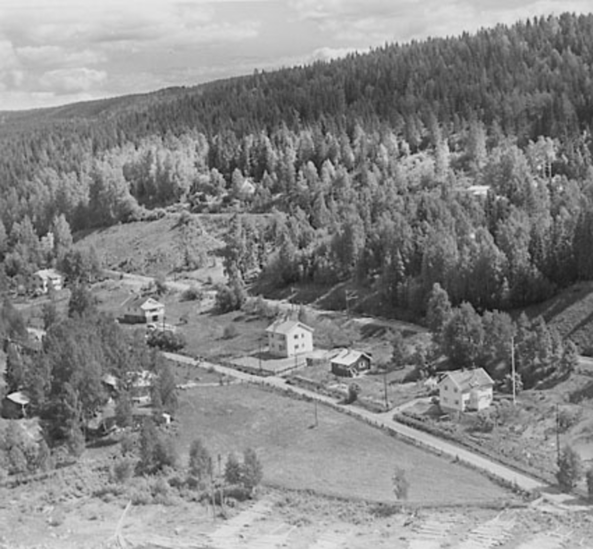 Widerøes Flyveselskap A/S, FLYFOTO, ESPA, FRA VENSTRE EIENDOMMENE SOLVOLL, SOLSTRAND TIDLIGERE PENSJONAT, SENERE HÆSTNES TRAPPEFABRIKK, . . . , . . . OG LIER. OMRÅDET BLE FRA GAMMELT AV KALT VÅDSANDENGEN (GNR 174-2). I DAG ER DETTE BRUKSNUMMERET Å FINNE SOM ØVERSTE SKOGSTEIG PÅ BILDET.