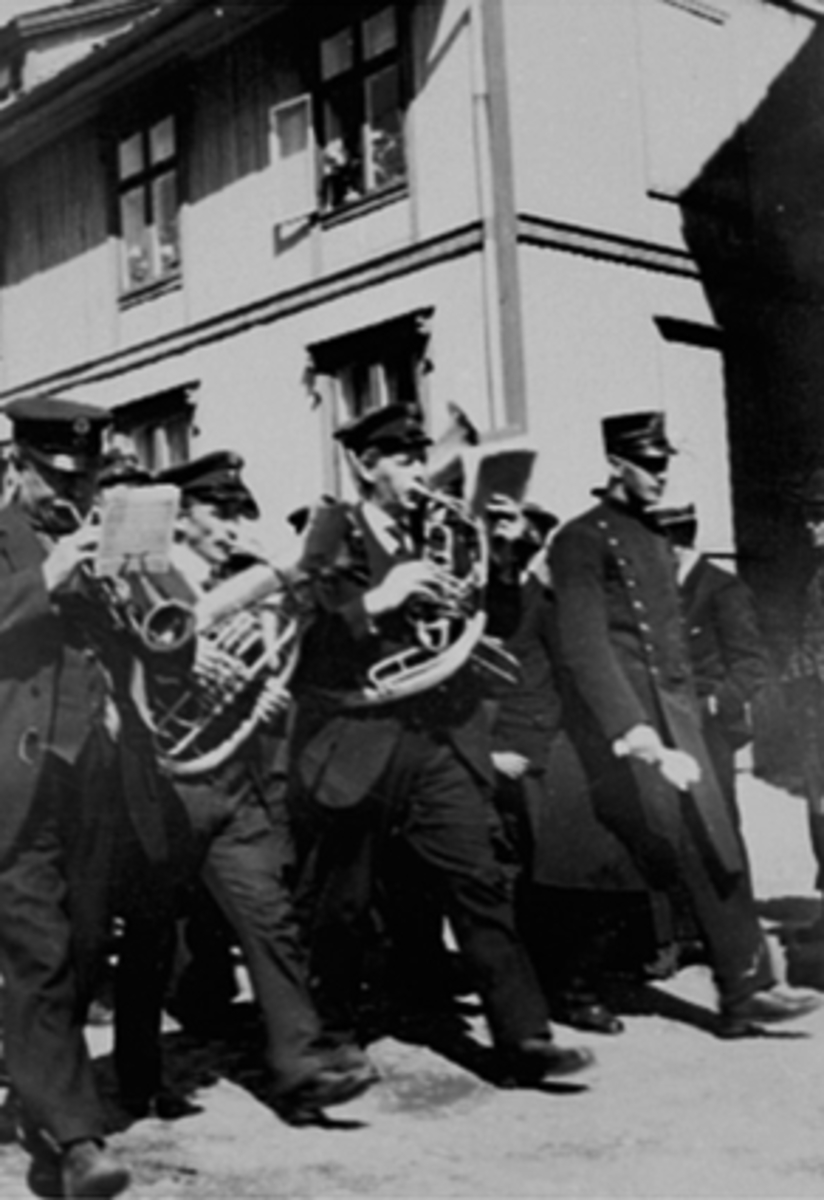 Anno Domkirkeodden, MUSIKK, MUSIKERE MARSJERER MED BLÅSEINSTRUMENTER I GRØNNEGATA, POLITIMANN