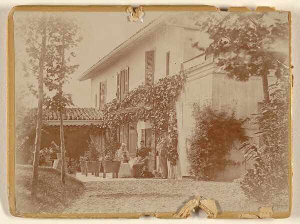 Unknown, [Group of people with two dogs at front of house, some seated]