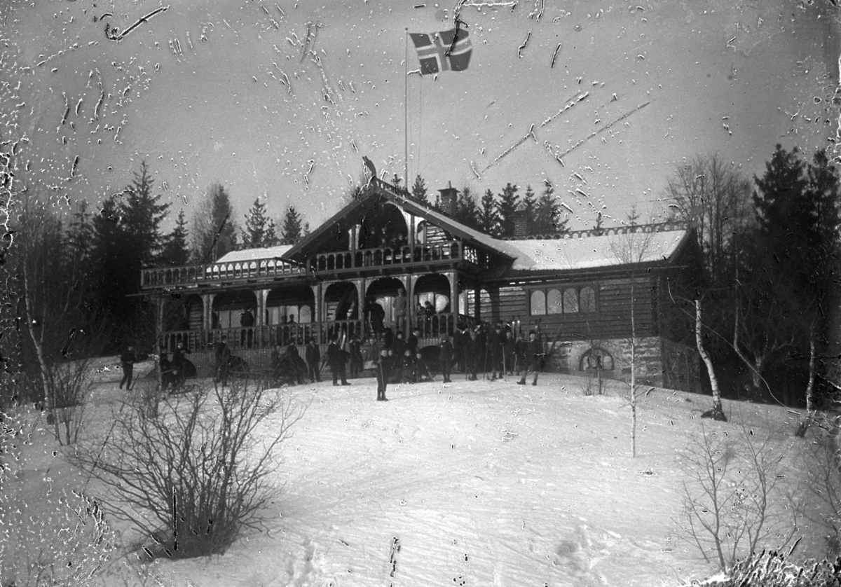 Johannes Larsen Alhaug, Skistua på Alhaug, Hamar. Gruppe mennesker med ski utenfor.