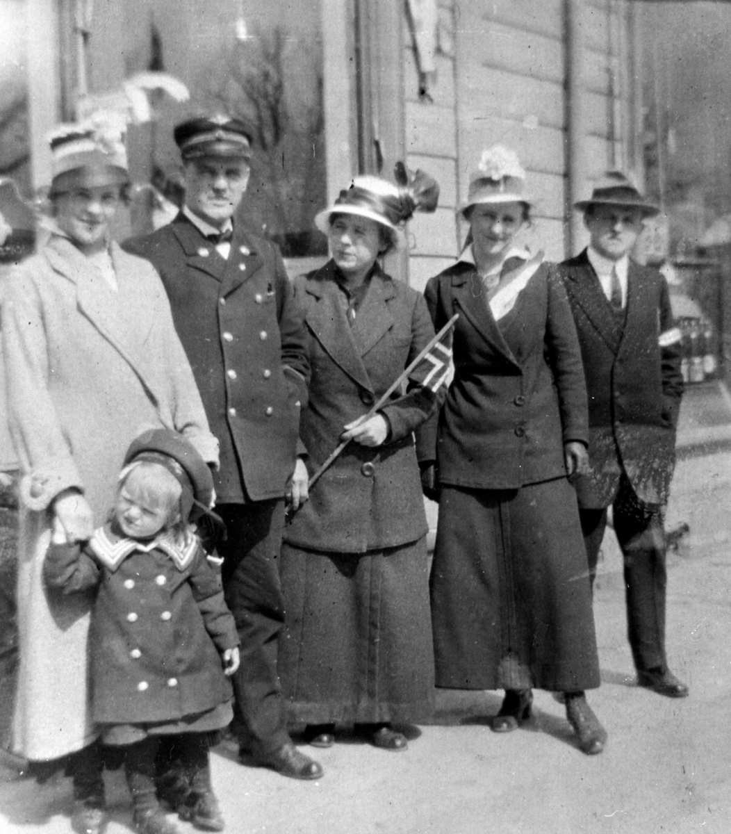 Anno Domkirkeodden, GRUPPE 6 VOKSNE OG LITEN JENTE PYNTET MED MATROSDRESS, MANN I NSB UNIFORM, FLAGG, 17 MAI? PETRUS JOHANNESSEN LENGST TIL HØYRE