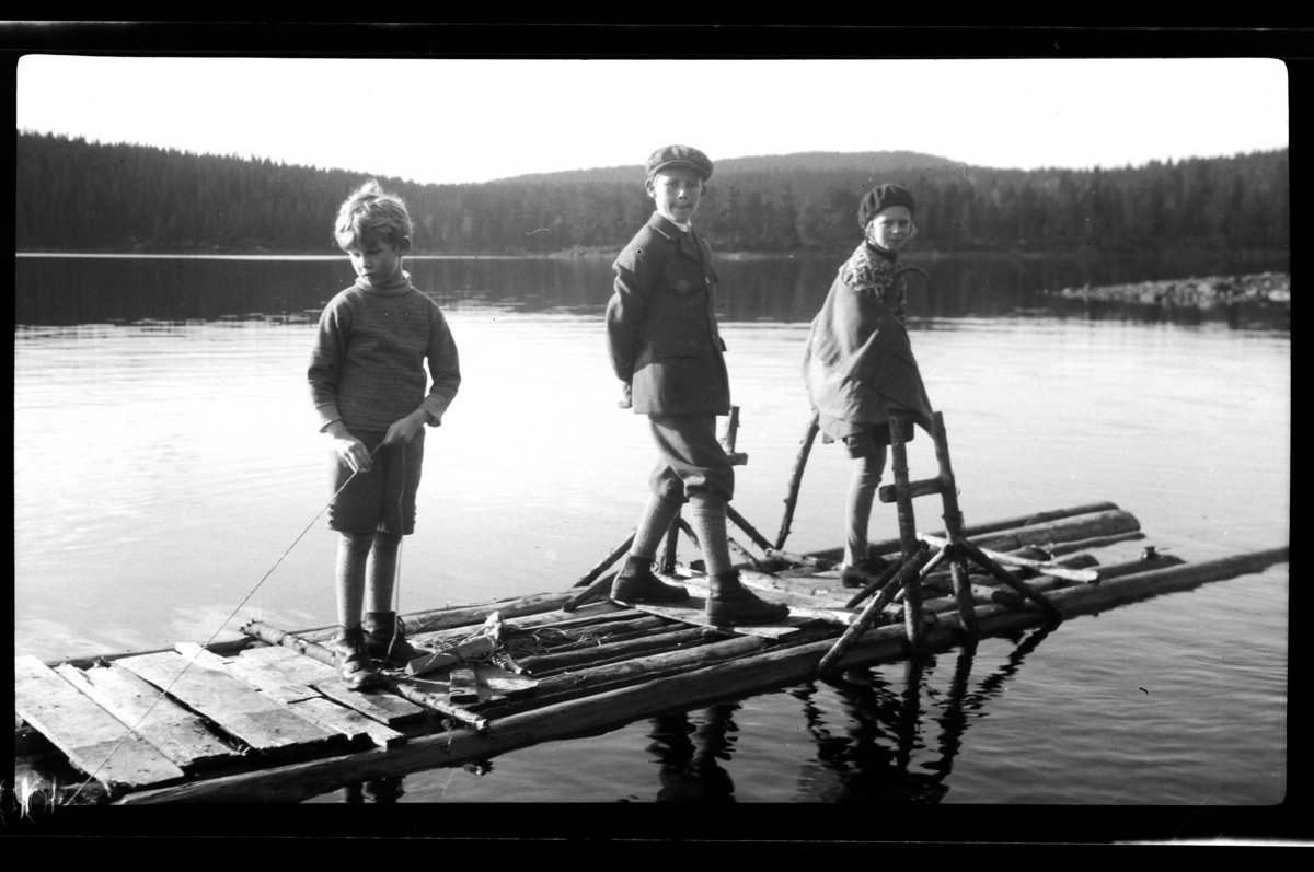 Rolf Sr. Sundt, Brødrene Rolf Sundt jr, og Julius Sundt står sammen med sin kusine Elsa Sundt på en en flåte, Ørfikse. Fotografert 1929.