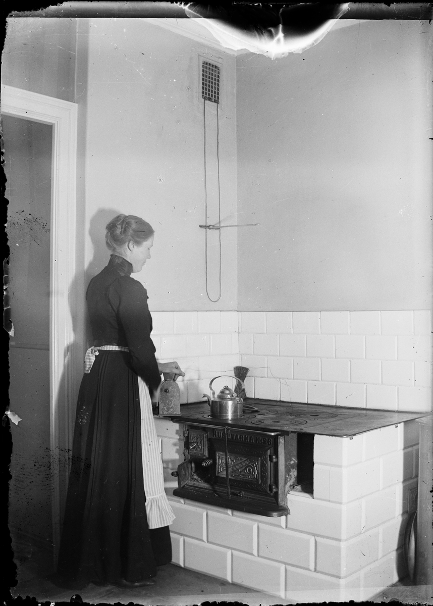 Skötsner-Edhlund, Ruth Skötsner stands by the wood stove and moth coffee, Östhammar, Uppland
