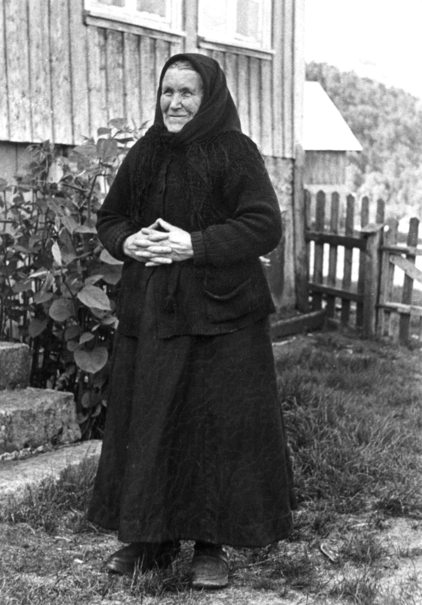 Anna Grostøl, Fru Johanne Sofie Seland, født 1858 står utenfor et hus. Fjotland, Kvinesdal, Vest-Agder 1941.