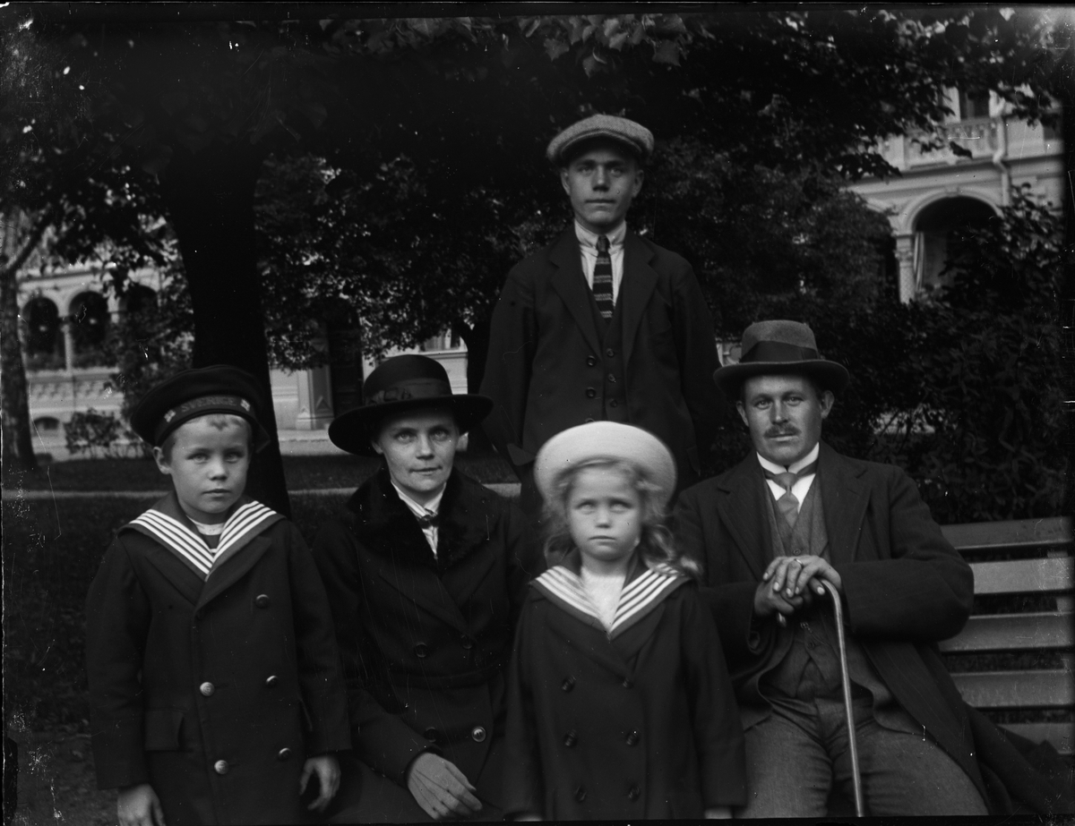 Okänd,, Woman, man and child sitting and standing by a park bench, Uppsala