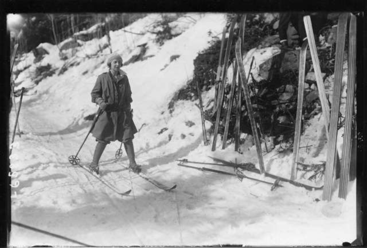 Hermann Christian Neupert, Kvinne på ski ankommer rasteplass med flere par ski stående i snøen.
