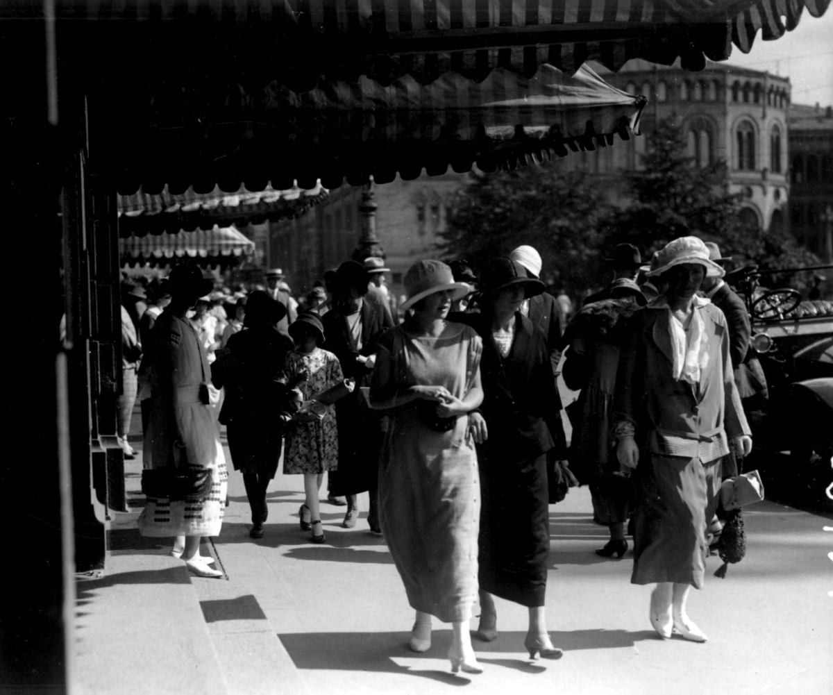 Hermann Christian Neupert, Bybilde fra Karl Johans gate mot Stortinget 1924. Fotgjengere med sommerklær. Kvinner med hatter. Bil skimtes i bakgrunnen..