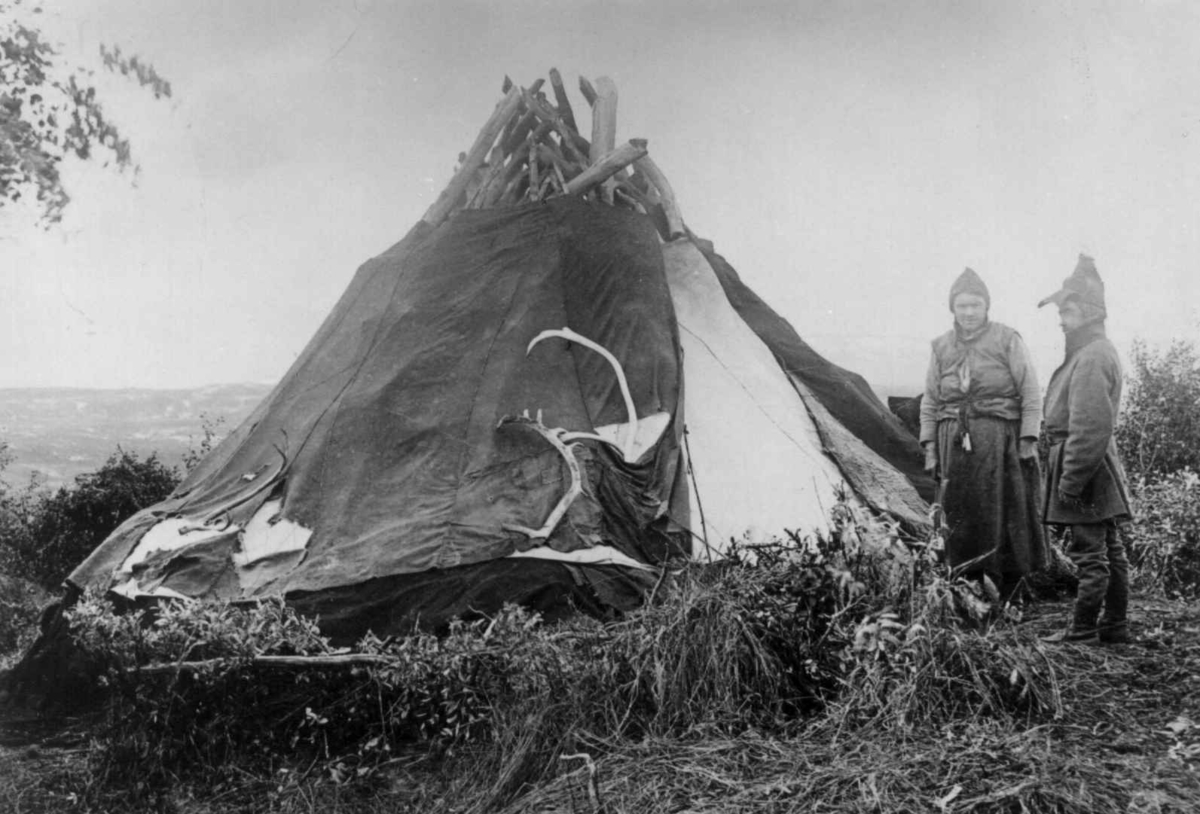 Axel Lindahl, To personer utenfor et telt, 1885-92. Oppl. v/ Bjørn Aarseth, Tromsø Museum: Han mener at bildet egentlig viser en gamme som er i en noe skrøpelig forfatning, dvs. at torven bl.a. har begynt å falle ned. Så har man da kledd gammen med en teltduk. - Det er for mange stenger til at det kan være et fl…