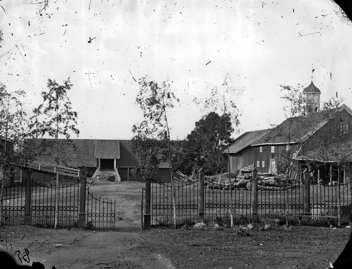 Jacob Tollesen Hoel, Hovinsholm gård, Helgøya i Ringsaker. Ytre gårdsplass sett fra indre. Gjerde, støpjern med trestolper. Foto Jacob Hoel 1885.