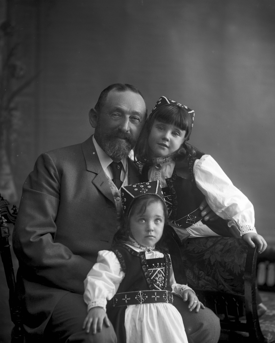 Gustav Borgen, Gruppeportrett, familiebilde. Voksen mann med to småpiker i bunad.