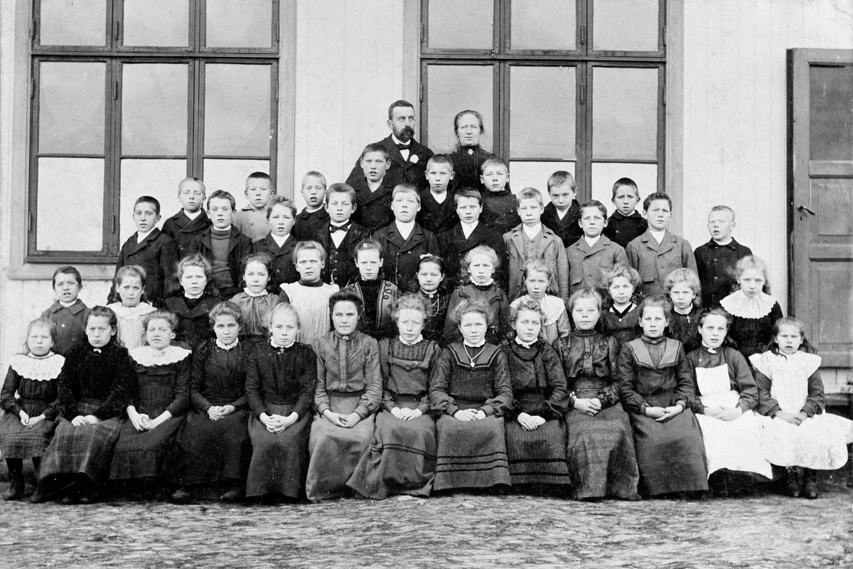 Anno Domkirkeodden, Gruppe 45 skoleelever ved Sørholtet Skole 1903-1904. Lærer Rostad i bakgrunnen. Rekke 1, nr. 1 fra høyre: Inga Hellum, (gift Andresen). nr 2 fra høyre: Anne Søbakken, (gift Engebakken). Rekke 2, nr 2 fra venstre: Julie Søbakken, (gift Haagensen). Rekke 3, nr 2 fra venstre: Johan Søbakken. Rekke 4, …