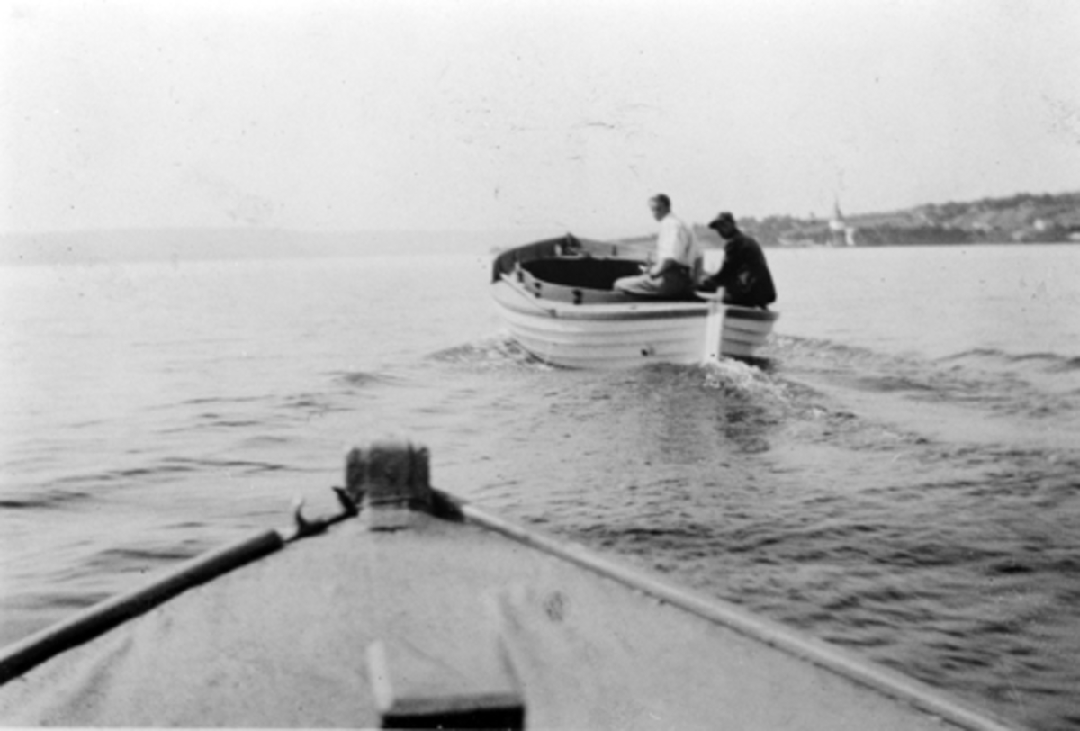 Anno Domkirkeodden, To mann i motorbåt på Mjøsa i Nessundet. I bakrunnen er Tingnes og Nes kirke, Hedmark.