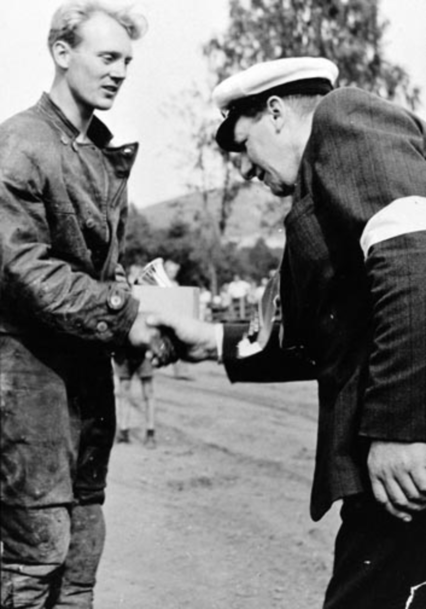 Anno Domkirkeodden, Fred Roger Steen ,mottar premie for raskest tid, speedwayrace på Brumunddal travbane. Birger Engli gratulerer. Birger Engli var formann i komiteen for arrangementet.