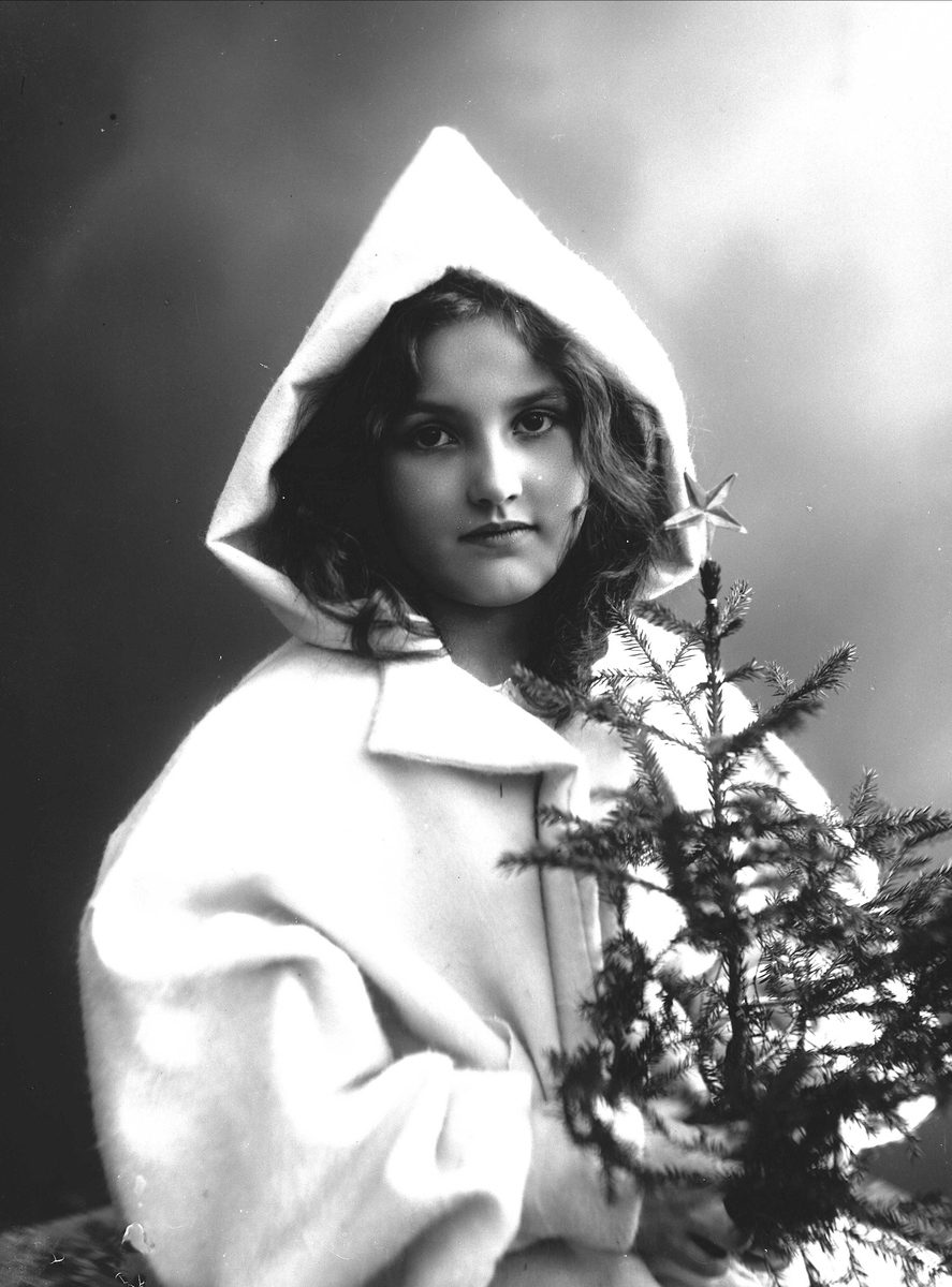 Solveig Lund, Julemotiv. Jente med kåpe med hette, holder juletre med stjerne.