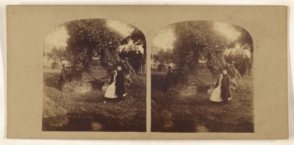 Unknown, [Couple near outdoor brick archway covered with ivy, another man standing next to it]