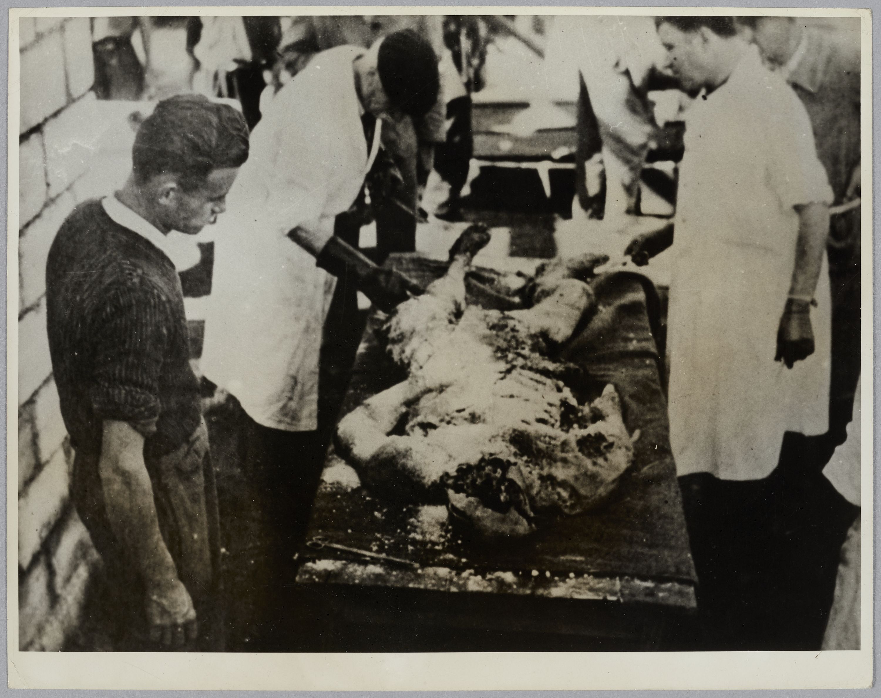United States Information Service, Cadavre exhumé d'un charnier examiné par plusieurs personnes