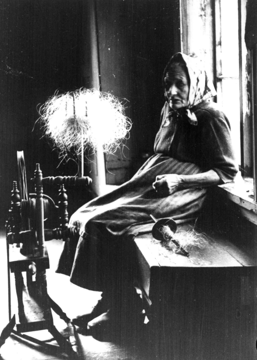 Anna Grostøl, Iveland, Vest-Agder 1941. Guri Neslebø spinner kutagl på håndrokk.