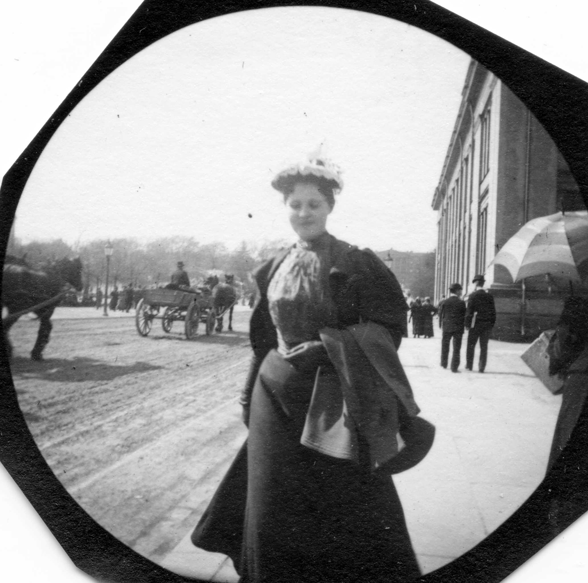 Fredrik Carl Mülertz Størmer, Frk. Faye senior spaserer langs Karl Johan, Oslo med jakke over armen ved Universitetet.