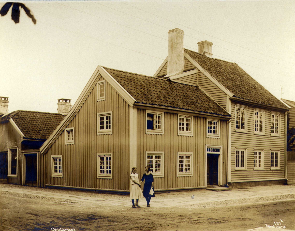 Anders Beer Wilse, Gateløp med trebygninger, Kristiansand, Vest-Agder. To jenter i forgrunnen.
