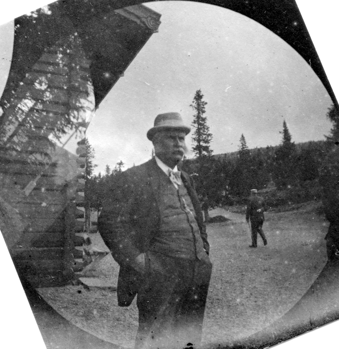Fredrik Carl Mülertz Størmer, Golå, Sør-Fron, Oppland. Fotografens svigerfar, generalkonsul C. Clauson, med hendene i lomma ved tømmerhus i skogen.