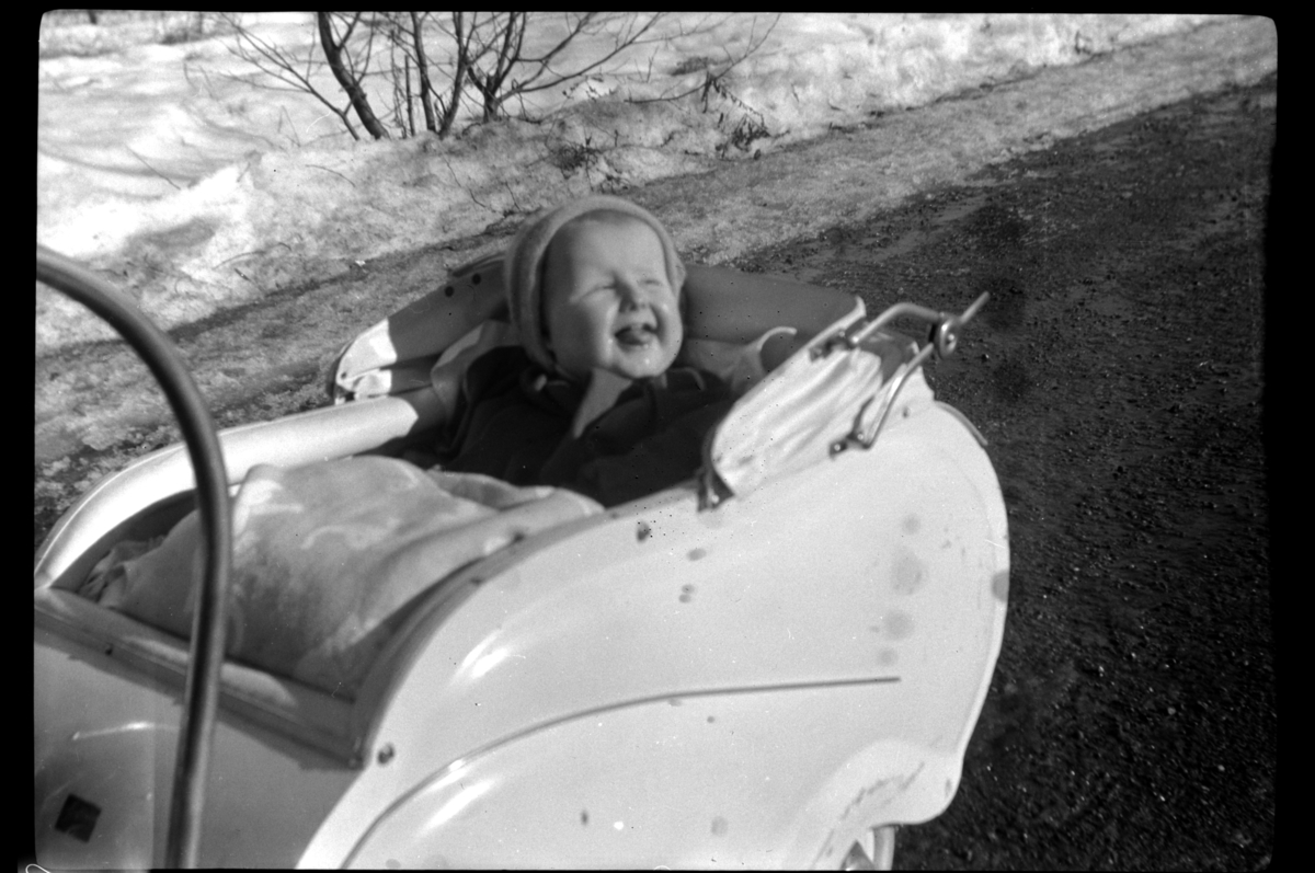 Rolf Sr. Sundt, Bjørn Sundt sitter sin en barnevogn en vinterdag. Fotografert 1952.