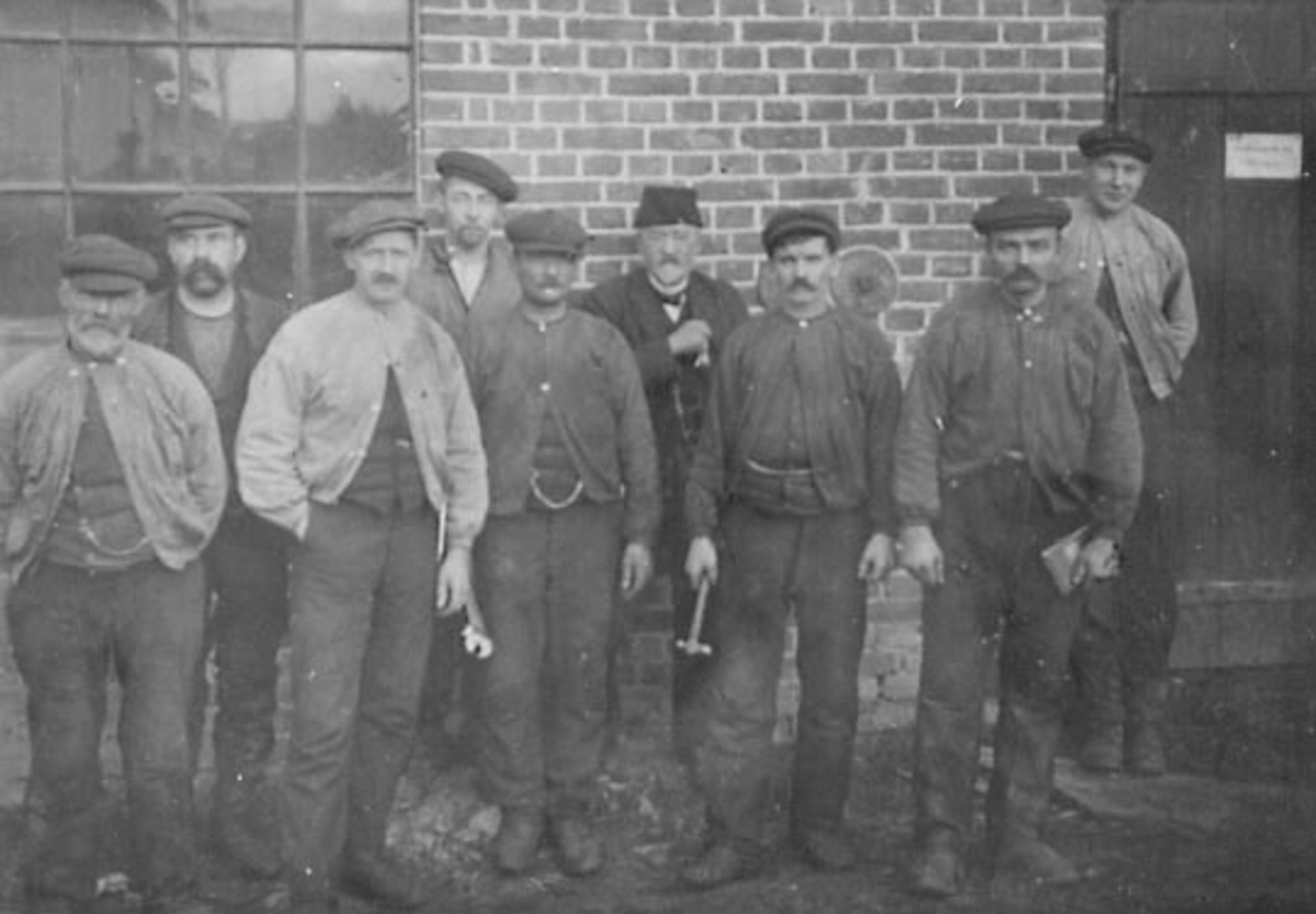 Anno Domkirkeodden, GRUPPE: 9 BRENNERIARBEIDERE FRA VENSTRE: MARTINUS SØSVEEN, UKJENT, NILS HUSE, JOHAN OLAUSSEN, UKJENT, OLE EGEBERG, FORAN, ROMEDAL BRENNERI