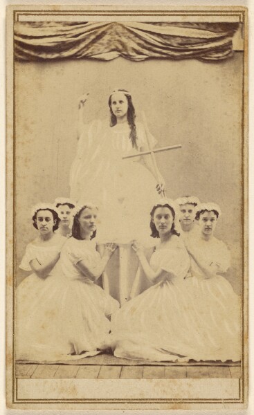 Unknown, [Female group portrait, six in white gowns kneeling, one standing holding a cross]