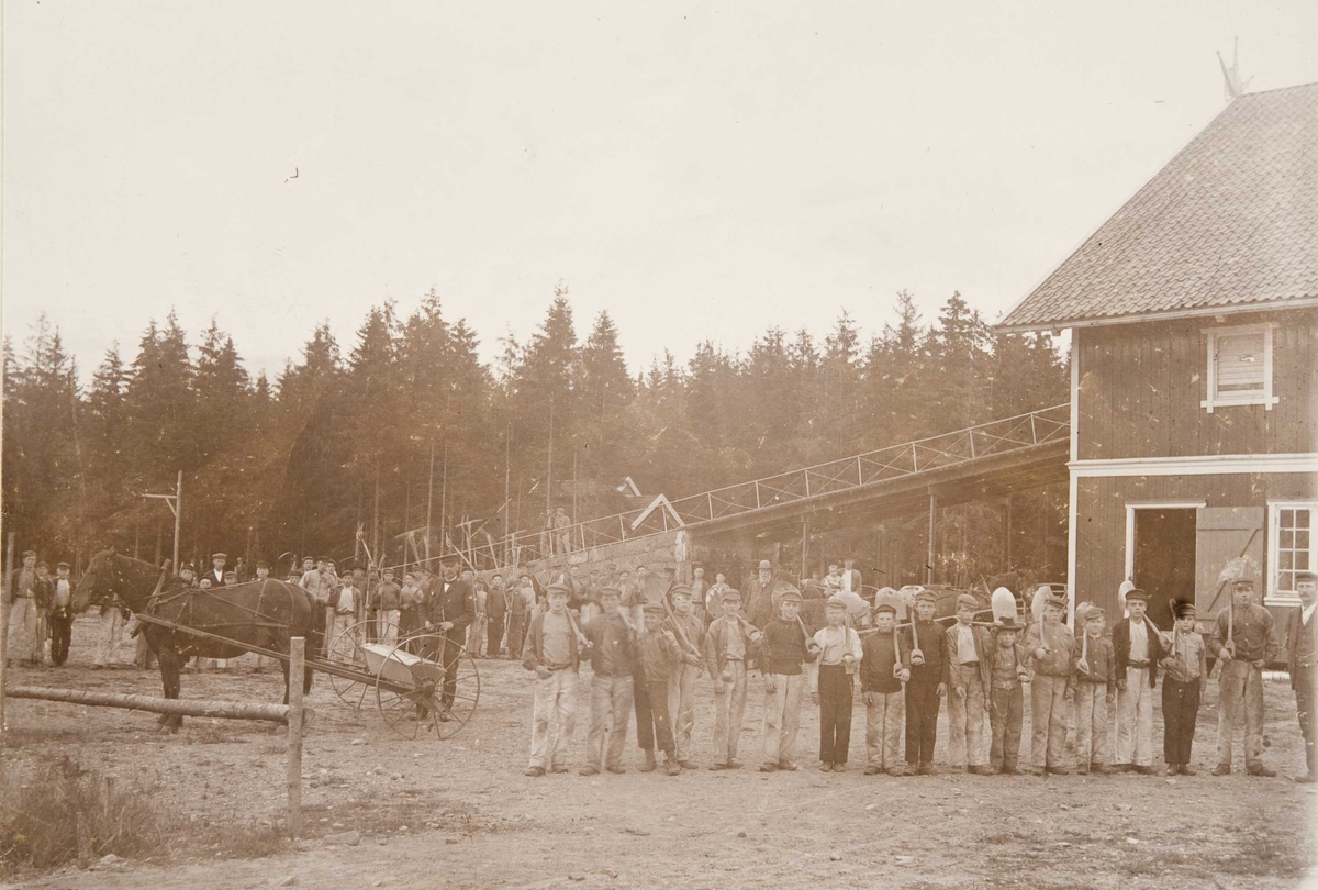 Berg & Høeg, Låvebygningen på Bastøy skolehjem, Bastøya, ca. 1903. Elevene står oppstilt utenfor med gårdsredskaper.