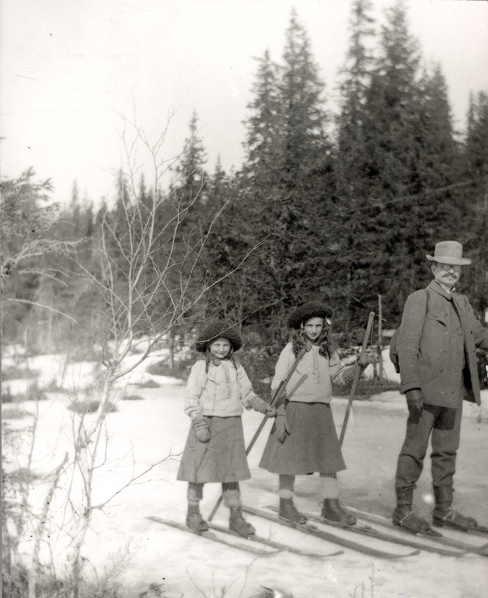 Axel Quinsgaard Wiborg, Gruppeportrett, Axel, Gudrun og Karen Q. Wiborg, Holoa seter, Hadeland, Jevnaker, Oppland, 1906. Pikene er fotografens døtre, alle på ski i skidrakter. Fra serie tatt av iseksportør Axel Quinsgaard Wiborg (d. 1944), til høyre på bildet.