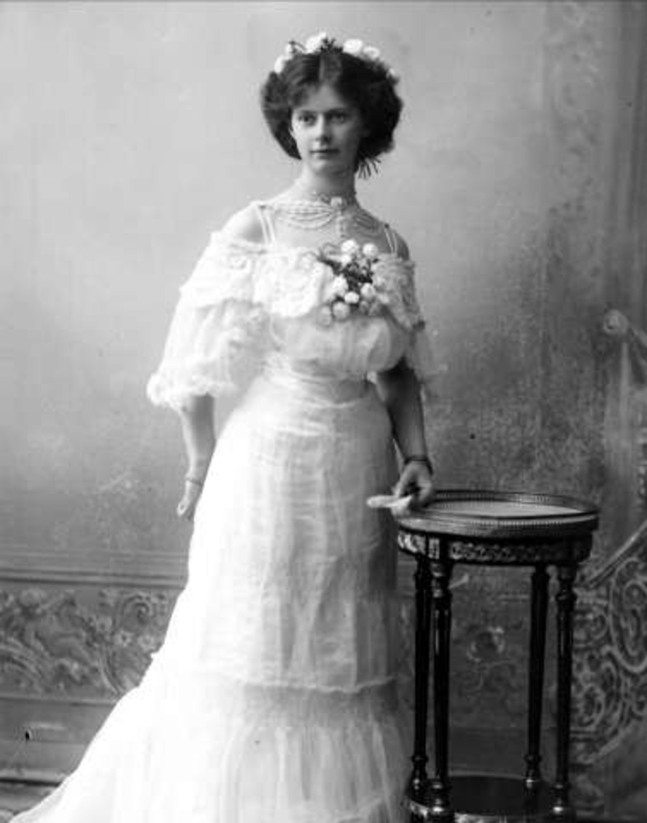 Gustav Borgen, Portrett, kvinne i hvit kjole, med blomst på brystet og håndvifte. Frøken C. Larsen, overrettssakfører Larsens datter(?)