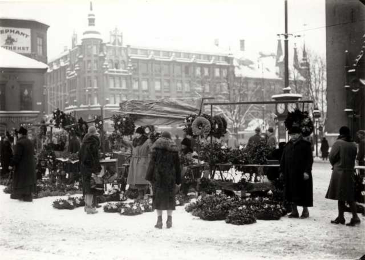 Hermann Christian Neupert, Stortorvet, Oslo 1930. Vinterbilde med torghandel. Kvinnelige kunder ses foran bodene.