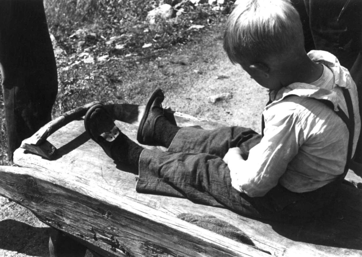 Anna Grostøl, En gutt sitter på en stampe til tøy. Fjotland, Kvinesdal, Vest-Agder 1941.