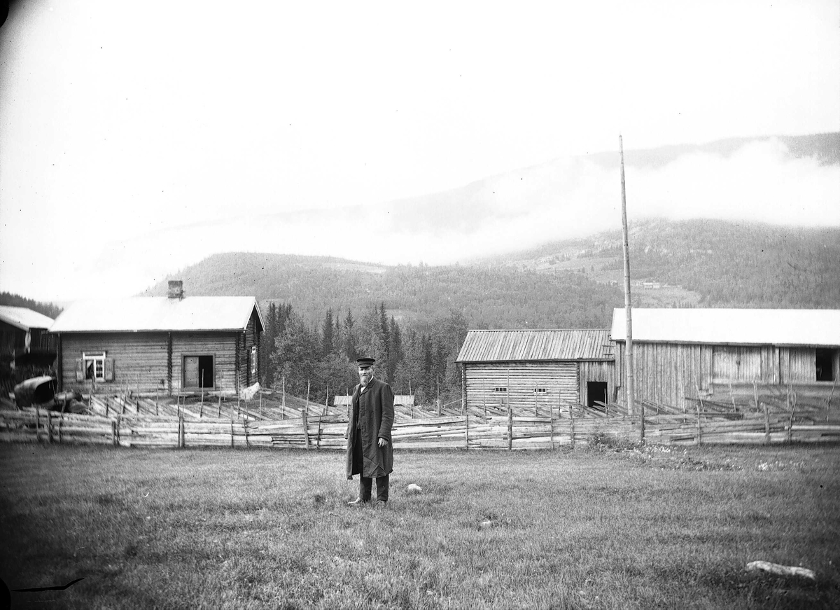 Axel Quinsgaard Wiborg, Kvisle, Numedal. Rollag, Buskerud, 1906. Mann står foran tømmergård med skigarder.